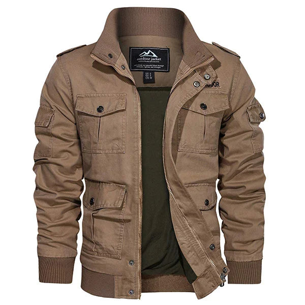 Une veste homme baroudeur en couleur kaki présentée sur un fond neutre. Ce vêtement robuste comporte plusieurs poches pratiques et une fermeture à glissière, avec des détails de boutons et d'épaulettes pour un look aventurier. Le style de la veste est renforcé par des poignets côtelés et un col montant, idéal pour un homme actif qui privilégie style et fonctionnalité.