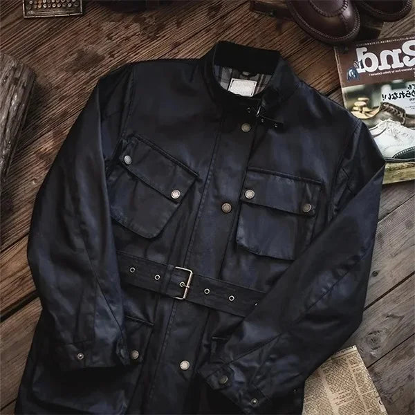 Veste saharienne homme Barbour noire posée à plat sur un fond en bois, ornée de plusieurs poches et d'une ceinture, illustrant un design classique et élégant pour un style aventurier et raffiné.